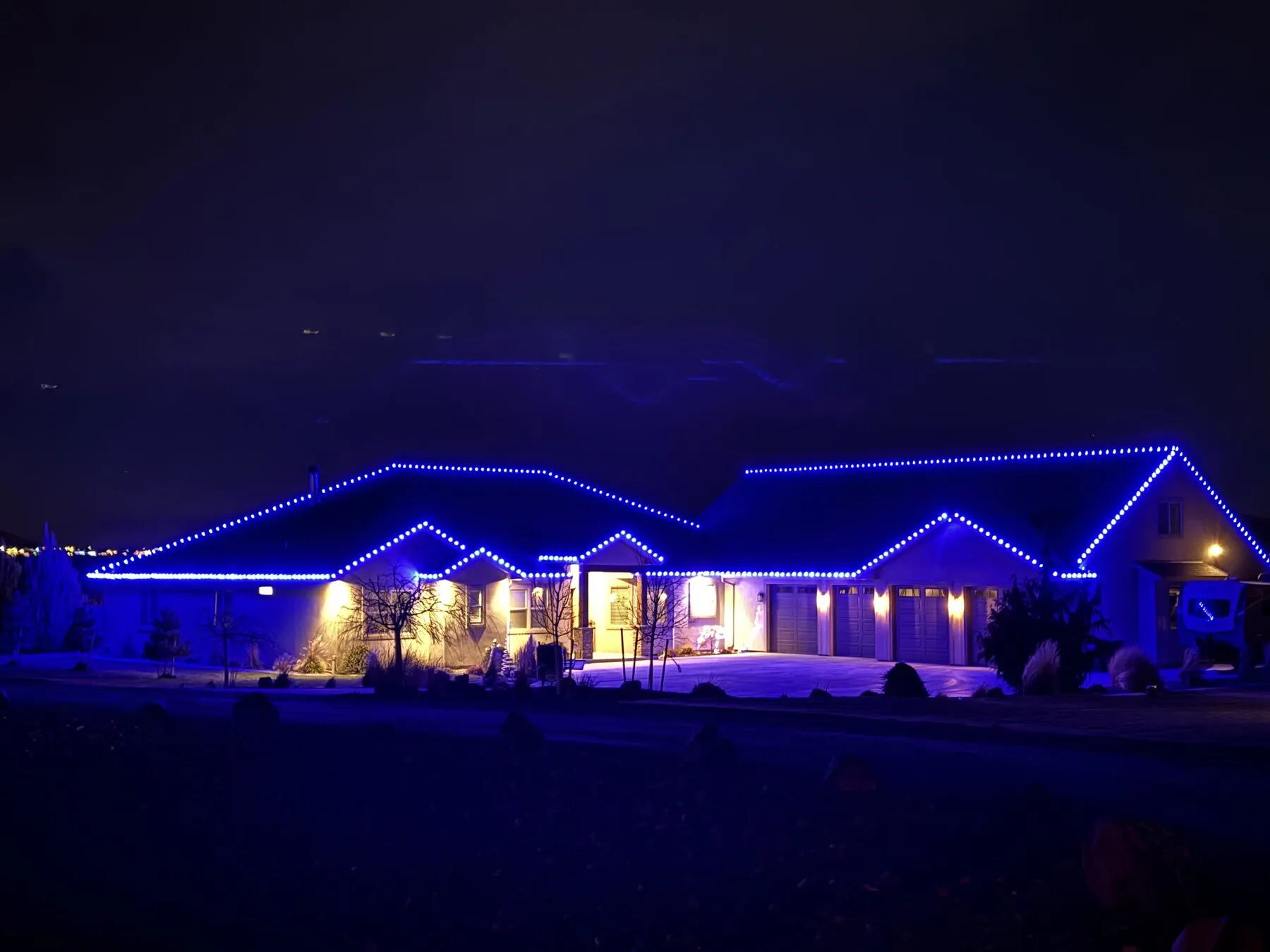 Permanent lights set to blue on a ranch home