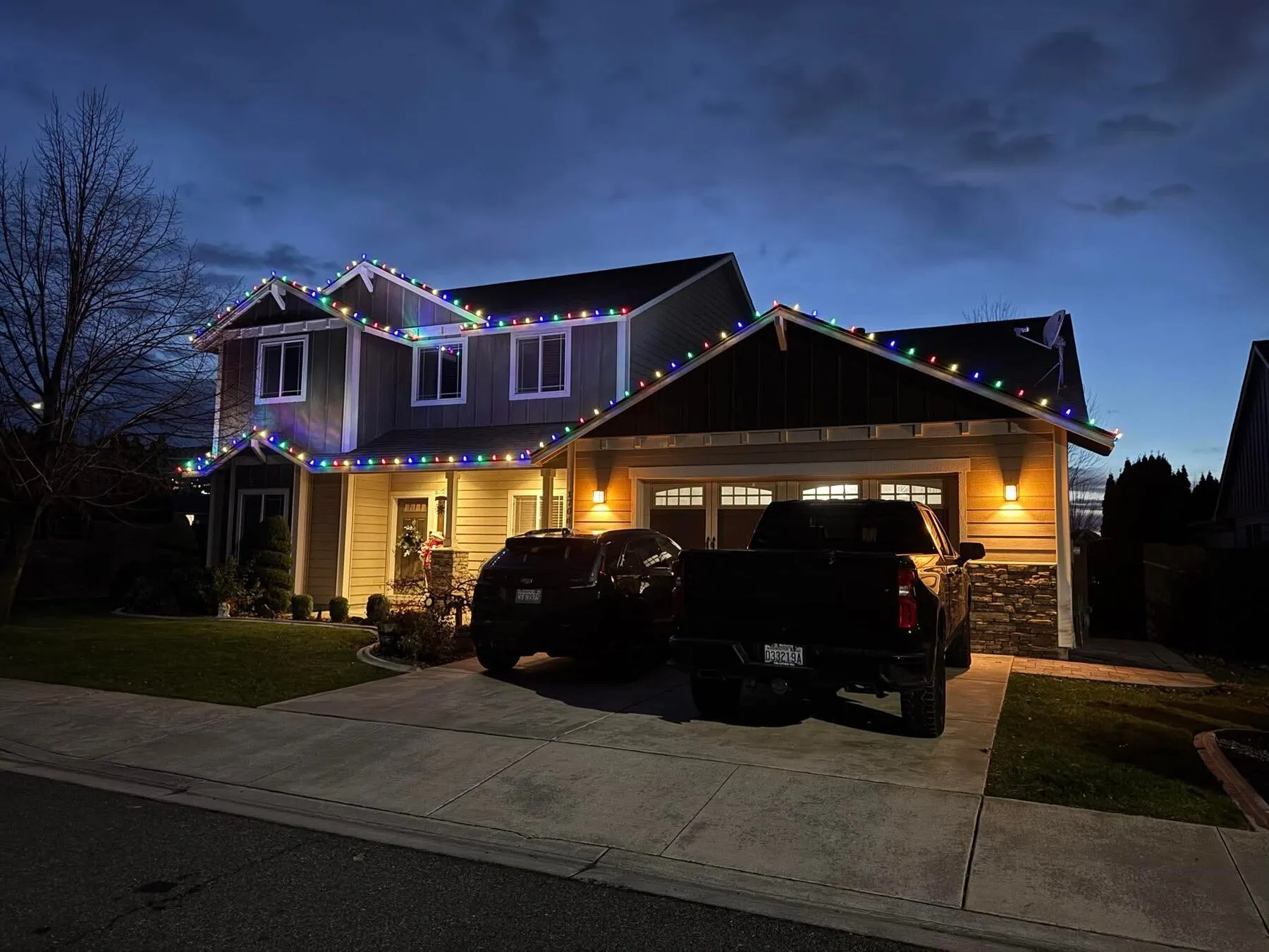 Two-story Tri-Cities home with multicolor C9 roofline lights at dusk